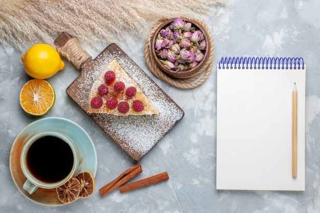 Draufsicht köstliche Kuchenscheibe mit Tasse Tee und Zitronenblock auf dem leichten Schreibtischkuchenkeks süßer Zuckerauflauf