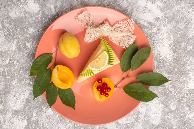 Draufsicht köstliche Kuchenscheibe mit Zitrone und Aprikosen in rosa Platte auf dem hellen Hintergrundkuchenkeks süßer Teig backen