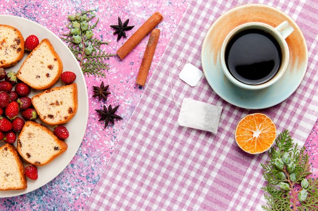 Draufsicht köstliche Kuchenscheiben mit Tasse Kaffee und frischen roten Erdbeeren auf rosa Schreibtischkuchen backen süßen Keksfarbkuchenkuchenzucker