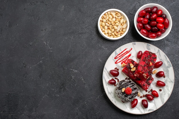 Draufsicht köstliche Kuchenstücke mit Nüssen und Hartriegeln auf Grauzone