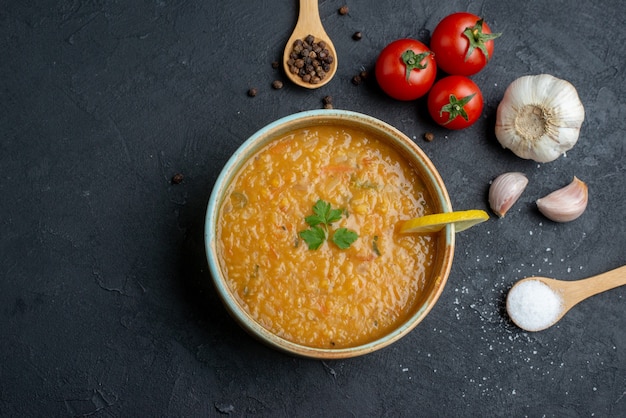 Draufsicht köstliche Linsensuppe mit Knoblauch und Tomaten auf dunkler Oberfläche