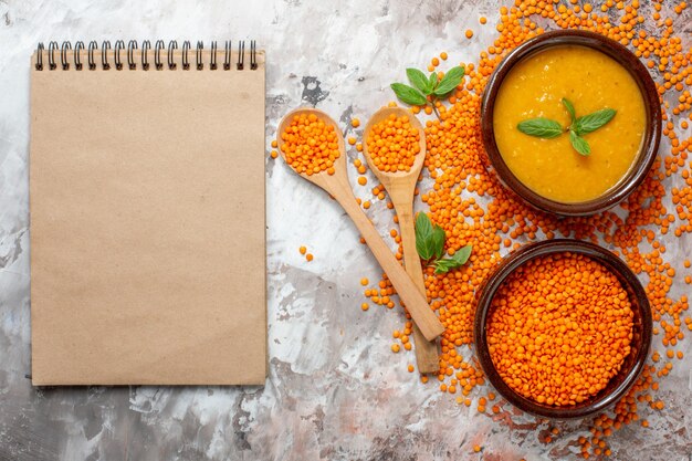 Draufsicht köstliche Linsensuppe mit rohen Linsen auf einer hellen Oberfläche Pflanzensuppe Farbe Lebensmittel Samenschale Foto