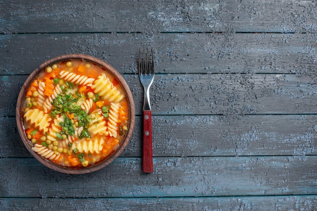 Draufsicht köstliche Nudelsuppe aus italienischer Spiralnudeln mit Grüns auf dem dunklen rustikalen Schreibtisch Abendessen Gericht italienische Nudelsuppe Soße