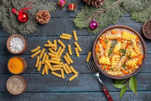 Draufsicht köstliche Nudelsuppe aus spiralförmiger italienischer Pasta mit Gewürzen auf dem dunkelblauen Schreibtischgericht Küche Farbsuppe Pasta