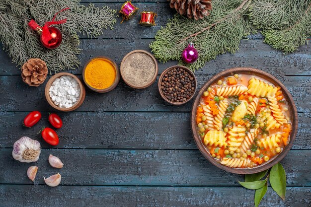 Draufsicht köstliche Nudelsuppe aus spiralförmiger italienischer Pasta mit Gewürzen auf der dunkelblauen Schreibtischküche Farbgerichtsuppe Pasta