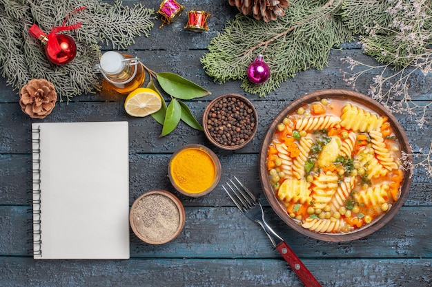 Draufsicht köstliche Nudelsuppe aus spiralförmiger italienischer Pasta mit Gewürzen auf dunkelblauem Schreibtisch Abendessen Küche Nudelfarbgerichtsuppe