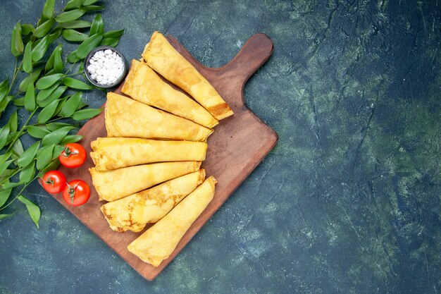 Draufsicht köstliche Pfannkuchen auf dunkler Oberfläche gerollt