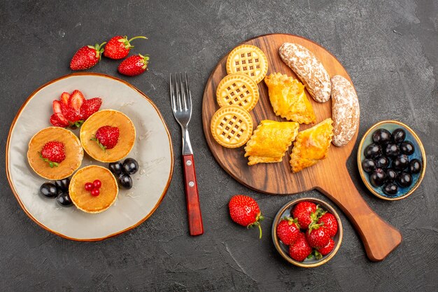 Draufsicht köstliche Pfannkuchen mit Früchten und Keksen auf dunkler Oberfläche Kuchenfrucht süßer Kuchen