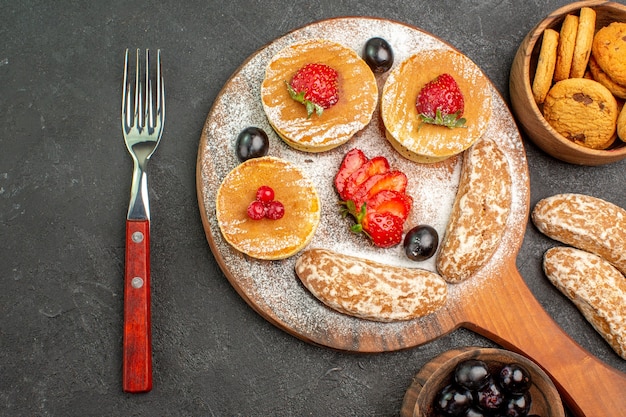 Draufsicht köstliche Pfannkuchen mit Früchten und süßen Kuchen auf dunklem Bodenkuchen-Nachtisch süß