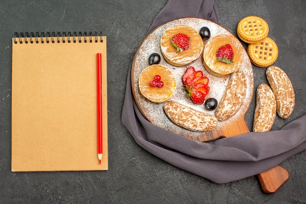 Draufsicht köstliche pfannkuchen mit früchten und süßen kuchen auf dunklem oberflächenkuchen-nachtisch süß