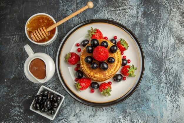 Draufsicht köstliche Pfannkuchen mit Honig und Früchten auf leichter Oberfläche Kuchen süße Früchte