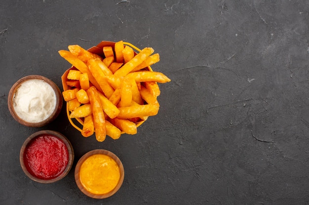 Draufsicht köstliche Pommes Frites mit Gewürzen auf dem dunklen Hintergrund Fast-Food-Kartoffelgericht Burger-Essen