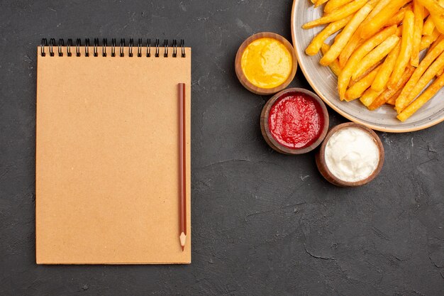 Draufsicht köstliche Pommes frites mit Gewürzen auf dunklem Hintergrund Gericht Kartoffel-Fast-Food-Burger-Essen