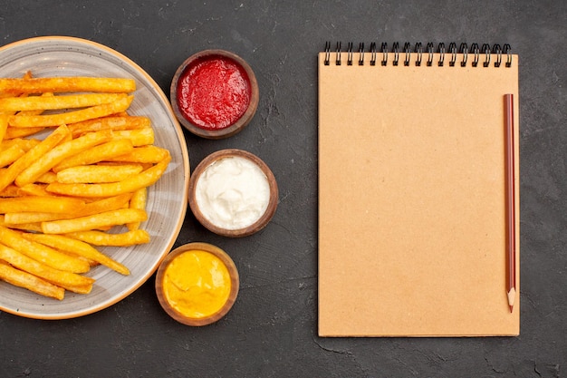 Draufsicht köstliche Pommes Frites mit Gewürzen auf dunklem Hintergrund Kartoffel-Fast-Food-Burger-Gericht