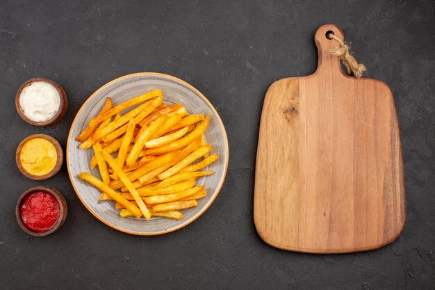 Draufsicht köstliche Pommes frites mit Gewürzen auf dunklem Hintergrund Kartoffelmahlzeit Burger Fast-Food-Gericht