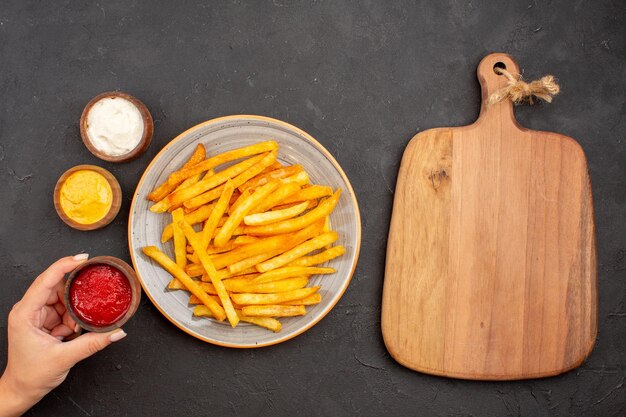 Draufsicht köstliche Pommes frites mit Gewürzen auf dunklem Hintergrund Kartoffelmahlzeit Fast-Food-Gericht Burger