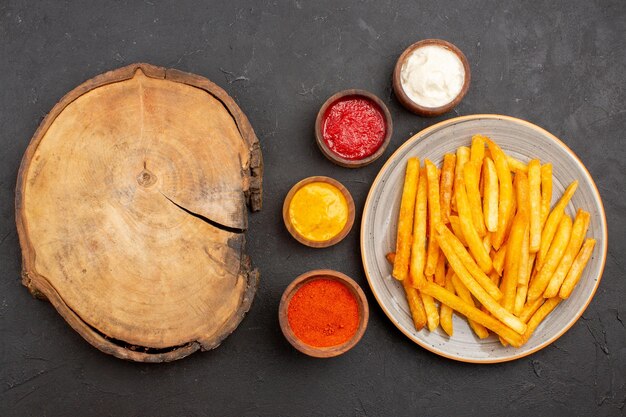 Draufsicht köstliche Pommes frites mit Soßen auf dem dunklen Hintergrund Fast-Food-Mahlzeit Kartoffelgericht Burger