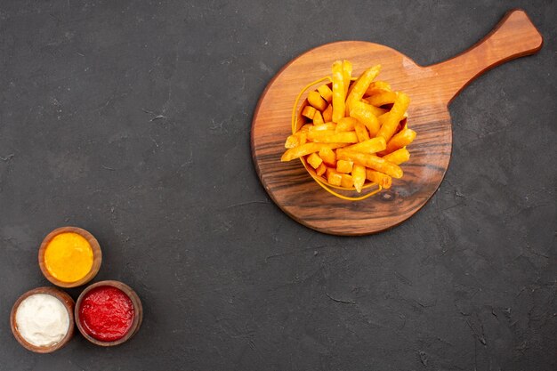 Draufsicht köstliche Pommes frites mit Soßen auf dunklem Bodengericht Burger-Fast-Food-Kartoffelmahlzeit