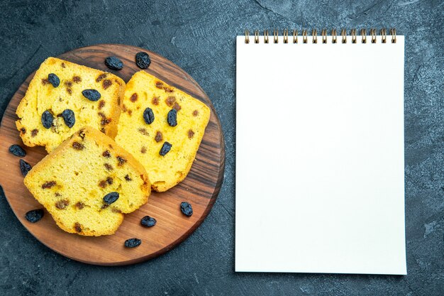 Draufsicht köstliche Rosinenkuchen, die auf dunkelblauem Raum geschnitten werden