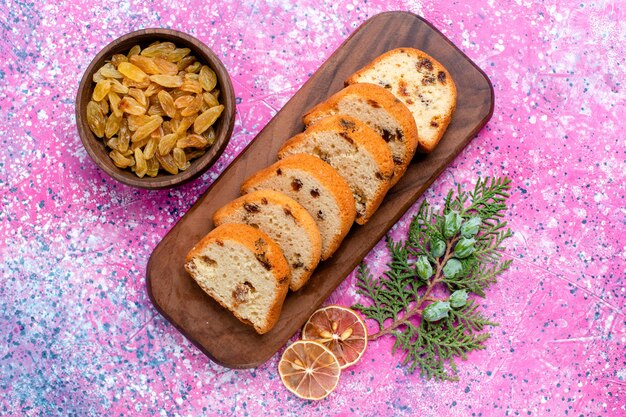 Draufsicht köstliche Rosinenkuchen geschnittene Torte auf dem rosa Schreibtisch backen Torte Zucker süße Kekskeksfarbe