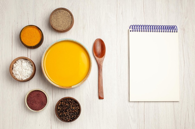 Draufsicht köstliche Sahnesuppe mit verschiedenen Gewürzen auf weißem Holztisch Suppensauce Mahlzeit Sahne Abendessen Gericht