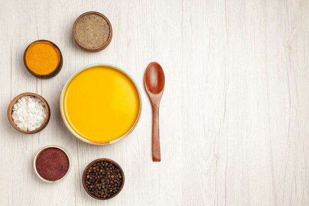 Draufsicht köstliche Sahnesuppe mit verschiedenen Gewürzen auf weißem Holztisch Suppensauce Mahlzeit Sahne Abendessen Gericht