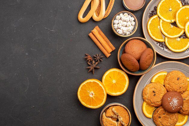 Draufsicht köstliche Sandkekse mit frischen Orangen auf dunklem Hintergrund Cookie Zucker Fruchtkeks süße Zitrusfrüchte