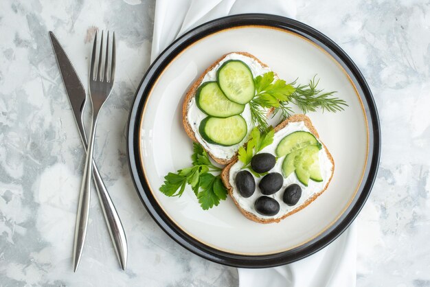 Kostenloses Foto draufsicht köstliche sandwiches mit gurken und oliven innerhalb der weißen oberfläche des tellers