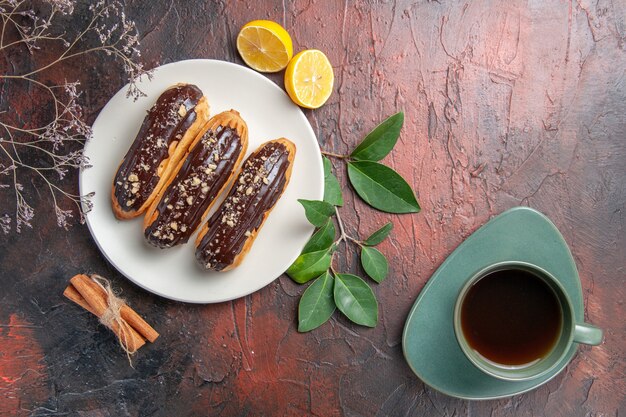 Draufsicht köstliche Schoko-Eclairs innerhalb des Tellers auf süßem Nachtisch der dunklen Tischkuchen-Torte