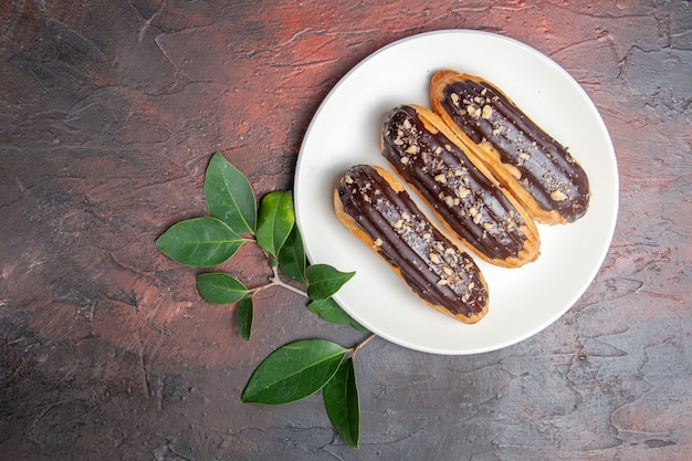 Draufsicht köstliche Schoko-Eclairs innerhalb Platte auf dunklem Tischdessert süßer Kuchen Torte