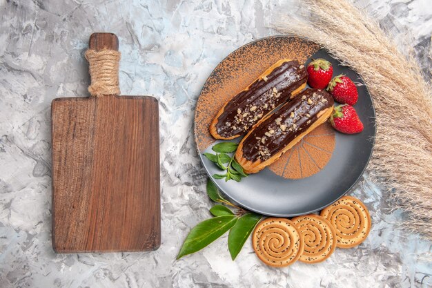 Draufsicht köstliche Schoko-Eclairs mit Keksen auf einem hellweißen Tischkuchen-Keks-Dessert