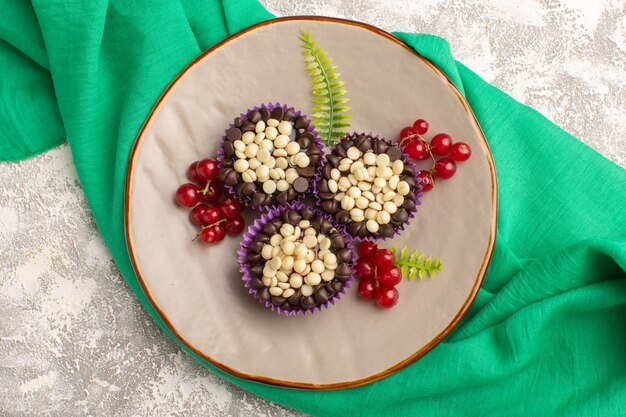 Draufsicht köstliche Schokoladenbrownies mit Preiselbeeren und Schokoladenstückchen auf dem leichten Schreibtischkuchenkeks süßer Teigauflauf