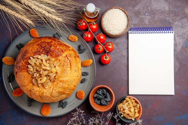 Draufsicht köstliche shakh plov gekochte Reismahlzeit mit Rosinen und Tomaten auf dem dunklen Hintergrundmahlzeitteig, der Reisdinner kocht