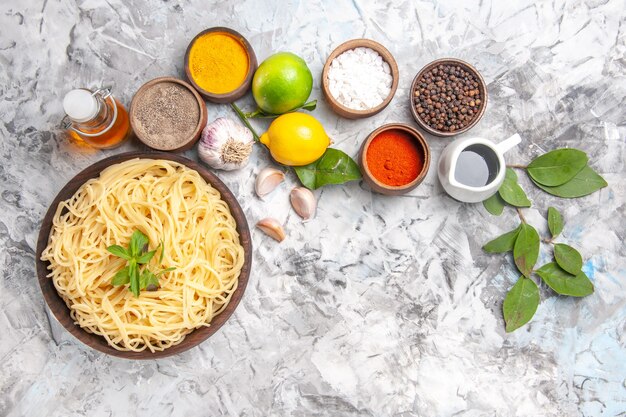 Draufsicht köstliche Spaghetti mit Gewürzen auf weißem Nudelteig