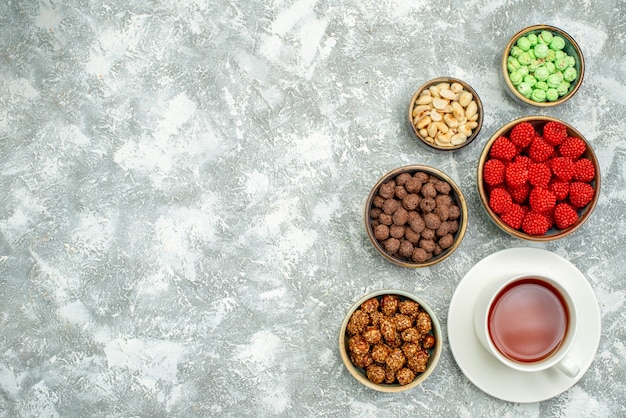 Draufsicht köstliche süße Bonbons mit Nüssen und Tasse Tee auf weißem Raum