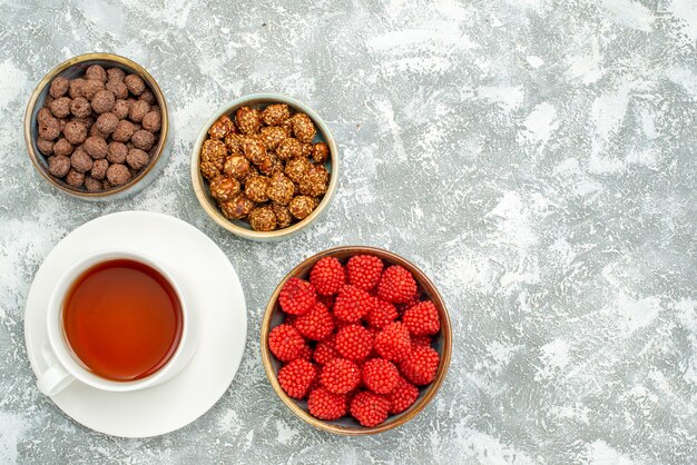 Draufsicht köstliche süße Bonbons mit Tasse Tee auf weißem Raum