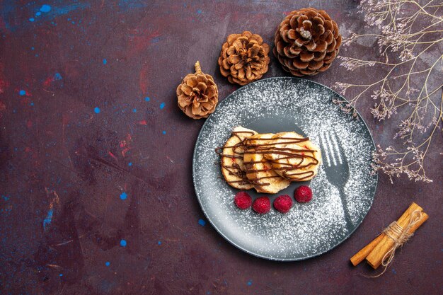 Draufsicht köstliche süße Brötchen geschnittener Kuchen für Tee innerhalb des Tellers auf dem dunklen Hintergrund Rollenkeks süßer Kuchenkuchen-Tee-Dessert