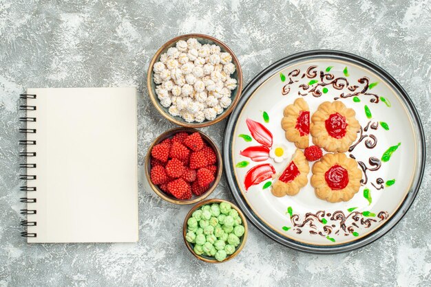 Draufsicht köstliche süße Kekse mit Bonbons auf hellweißem Hintergrund Kuchen süßer Keksplätzchentee