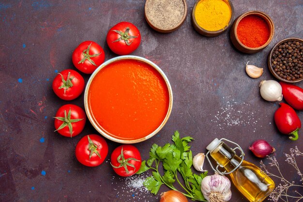 Draufsicht köstliche Tomatensuppe mit frischen Tomaten und Gewürzen auf dunklem Hintergrund Tomatengericht Abendessen Suppe Sauce Mahlzeit