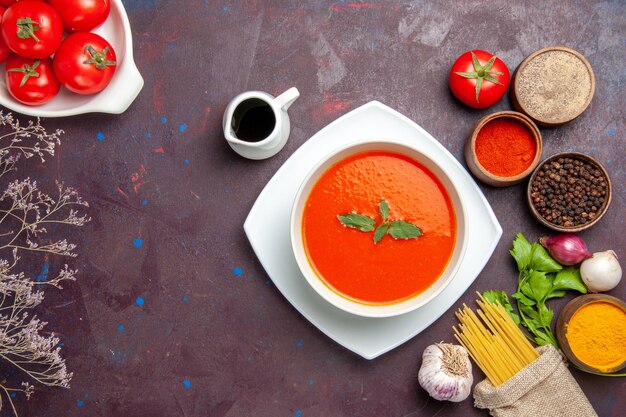 Draufsicht köstliche Tomatensuppe mit frischen Tomaten und Gewürzen auf dunklem Schreibtischgericht Mahlzeit Sauce Tomatenfarbensuppe