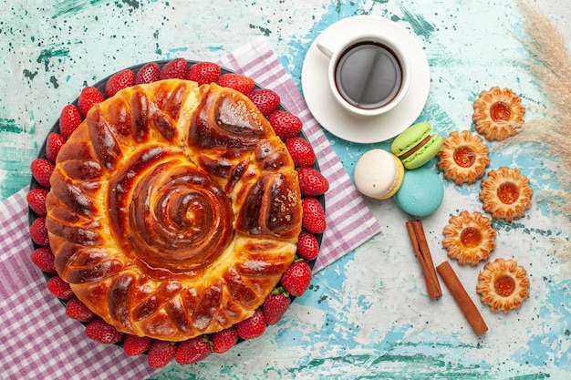 Draufsicht köstliche Torte mit Erdbeer-Macarons und Tasse Tee auf der blauen Oberfläche