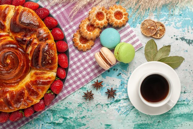 Draufsicht köstliche Torte mit Erdbeeren und Tasse Tee auf blauer Oberfläche