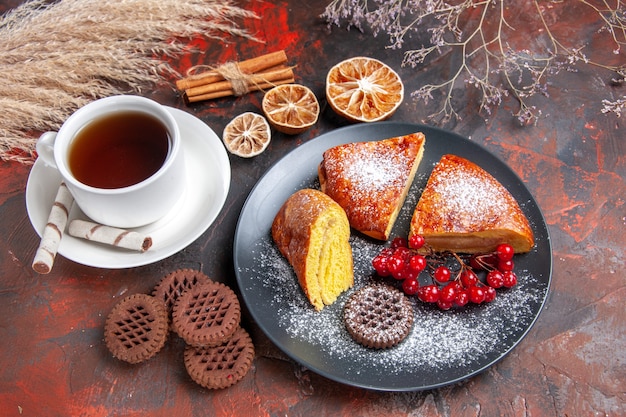 Draufsicht köstliche Torte mit Tasse Tee auf dunklem Tischkuchen süßer Tortentee