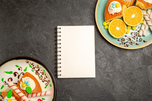 Draufsicht köstliche Tortenscheiben mit frischen Mandarinen auf grauem Hintergrund Tortenfrucht-Süßigkeiten-Teig-Teekuchen