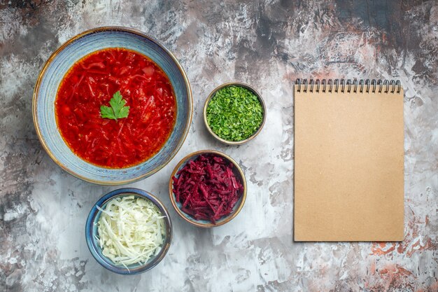 Draufsicht köstliche ukrainische Rübensuppe des Borschtsches mit frischem Kohl und Grüns auf weißem Hintergrund