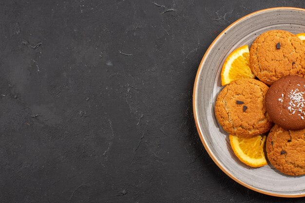 Draufsicht köstliche Zuckerkekse mit geschnittenen Orangen im Teller auf dem dunklen Hintergrund Zuckerfruchtkeks süße Kekse