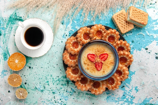 Draufsicht köstliche zuckerkekse mit waffeln tasse kaffee und erdbeerdessert auf dem blauen schreibtisch