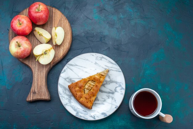 Draufsicht köstlicher Apfelkuchen in Innenplatte mit Tee und Äpfeln auf dunkelblauem Hintergrund Obstkuchen Kuchen Zucker süß geschnitten