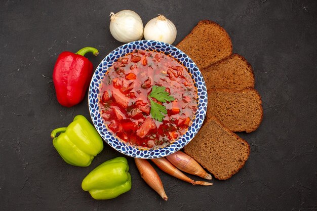 Draufsicht köstlicher Borschtsch mit frischem Gemüse und Brotlaiben auf dem dunklen Raum