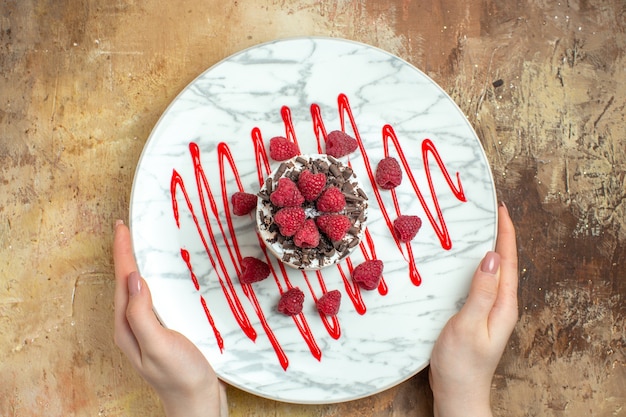 Kostenloses Foto draufsicht köstlicher cremiger kuchen im teller mit himbeeren auf braunem hintergrund